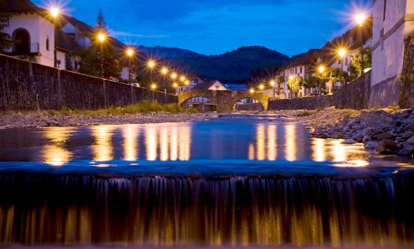 Vista nocturna de Ochagavía desde el centro del río con un salto de agua en primer plano